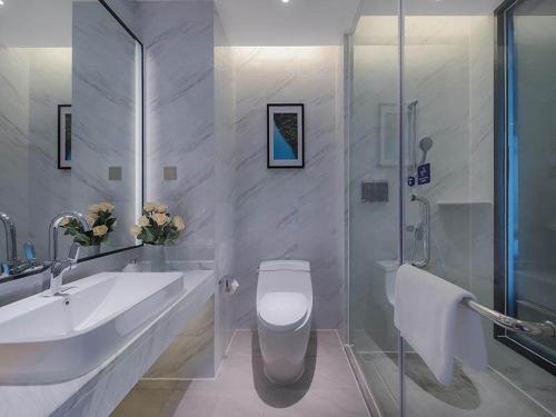 a bathroom with a sink and a toilet and a shower at Kyriad Marvelous Hotel Huizhou Boluo Longxi in Boluo