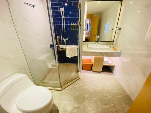 a bathroom with a toilet and a shower and a sink at Kyriad Marvelous Hotel Shantou Railway Station in Shantou