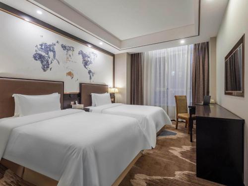 a hotel room with two beds and a desk at Kyriad Marvelous Hotel Weihai Railway Station in Weihai