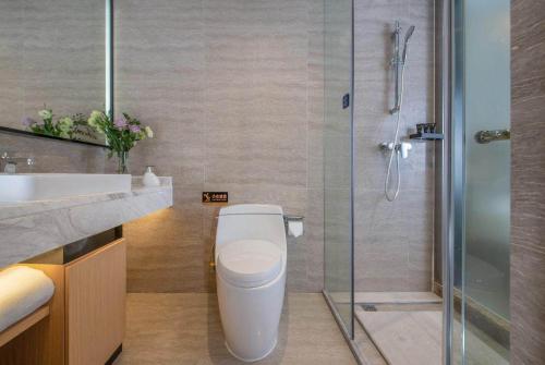 a bathroom with a toilet and a glass shower at Kyriad Marvelous Hotel Shenzhen Longhua Mission Hills Bamboo Village Subway Station in Bao'an