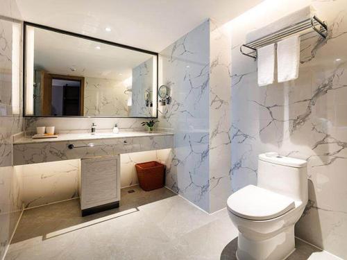 a bathroom with a toilet and a sink and a mirror at Kyriad Marvelous Hotel Shenzhen Linheng Plaza Liuyue Subway Station in Liantang