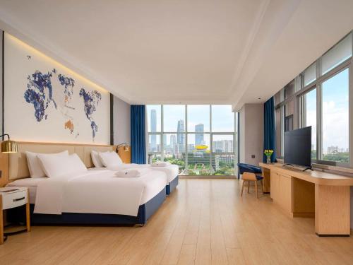 una camera d'albergo con 2 letti, una scrivania e una TV di Kyriad Marvelous Hotel Dongguan Municipal Government a Dongguan