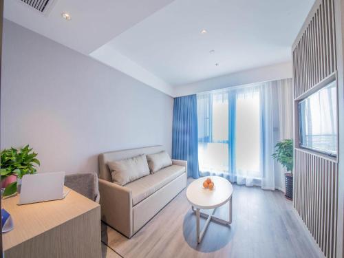 a living room with a couch and a table at Kyriad Marvelous Hotel Qinhuangdao Nandaihe in Qinhuangdao