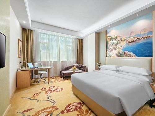 Schlafzimmer mit einem großen weißen Bett und einem Schreibtisch in der Unterkunft Vienna International Hotel Zhejiang Wenzhou Ruian Tangxia in Ruian