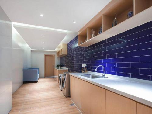 a kitchen with a sink and a blue brick wall at Kyriad Marvelous Hotel Suzhou Wujiang People Square in Suzhou