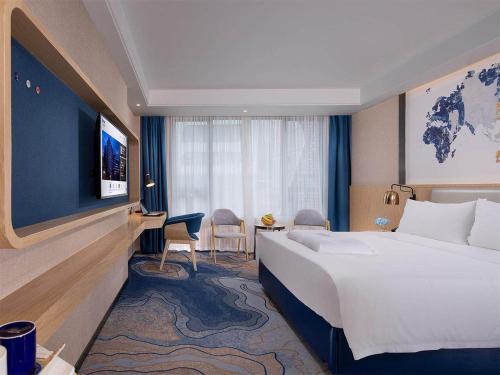 a hotel room with a large bed and a television at Kyriad Hotel Zhongshan University of Science and Technology in Zhongshan
