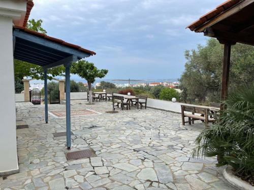 eine Terrasse mit Bänken und Tischen auf einer Steinterrasse in der Unterkunft Cozy studio in Skala, Agistri in Skala