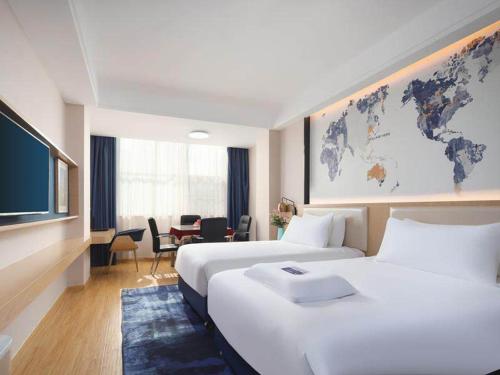 una habitación de hotel con 2 camas y un mapa mundial en la pared en Kyriad Marvelous Hotel Yiyang Ziyang en Yiyang