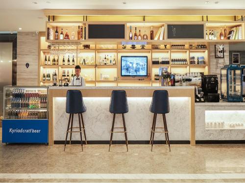 a bar in a store with three stools at Kyriad Marvelous Hotel Suzhou Guanqian Street and Shiquan Street in Suzhou