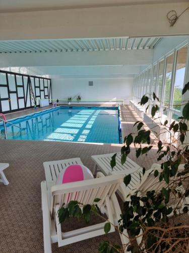 a large swimming pool with white chairs and a swimming pool at Hotel Kurhaus Uhlenberg in Bad Münstereifel