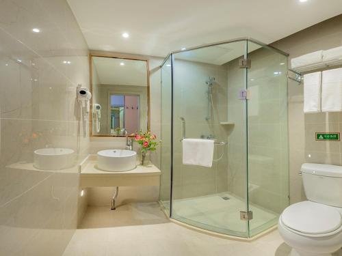a bathroom with a glass shower and a toilet at Vienna Classic Hotel Mudanjiang Railway Station in Mudanjiang