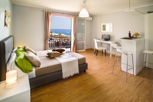 a bedroom with a bed and a table and a kitchen at Appartamento Mare Marconi in Letojanni