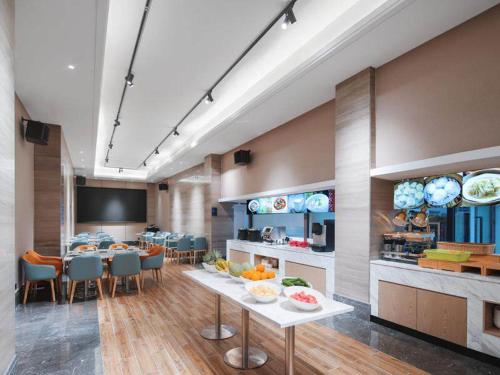 a room with a kitchen and a table with fruits on it at Kyriad Marvelous Hotel Shenzhen Guangming Zhenmei Subway Station in Bao'an