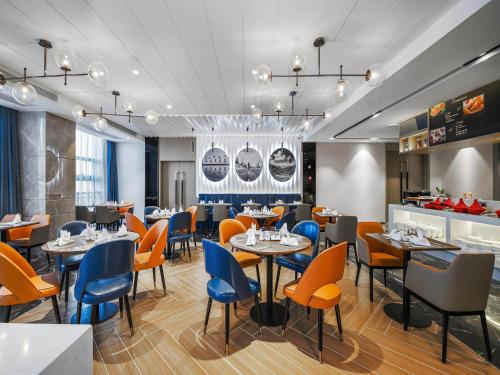 南昌市にあるKyriad Marvelous Hotel NanChang Xiang Lake Jinsha Avenueのテーブルと椅子のあるレストラン、バー