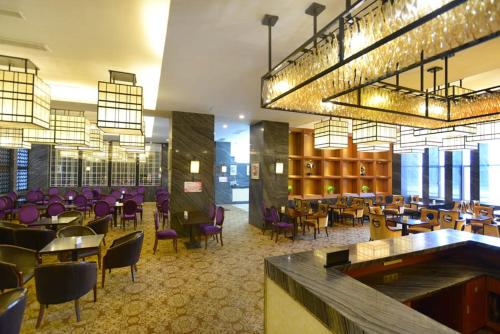 un vestíbulo con un restaurante con mesas y sillas moradas en Vienna International Hotel Yangzhou Wanda Lippo Plaza, en Yangzhou