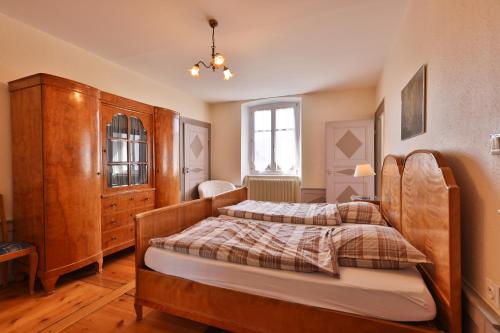 a bedroom with two beds and a wooden cabinet at Ancien Presbytère Albert Schweitzer in Gunsbach