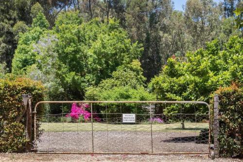 a gate to a garden with pink flowers at Hoogwater Family House in Wolseley
