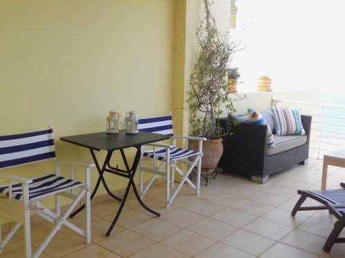 un patio con tavolo, sedie e divano di Most Astonishing Sunset a Vráchos