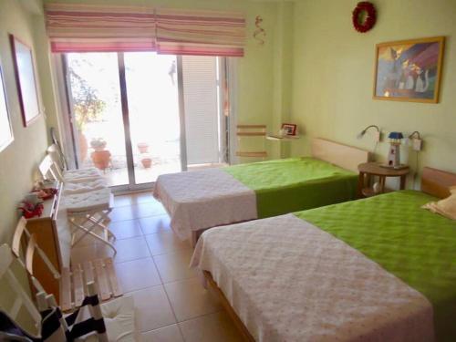 una camera con due letti con lenzuola verdi e bianche di Most Astonishing Sunset a Vráchos