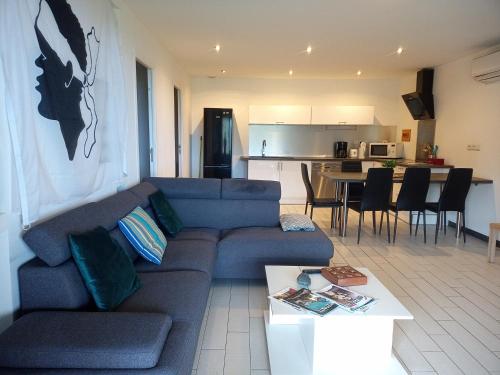 un salon avec un canapé bleu et une cuisine dans l'établissement Cap CORSE URIBELLINU 2 formule petit déjeuner, à Santa-Maria-di-Lota