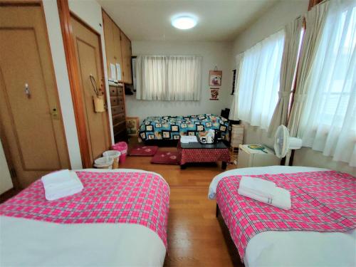 a small room with two beds and a couch at 民泊マエダハウス B&B Maeda House in Aira