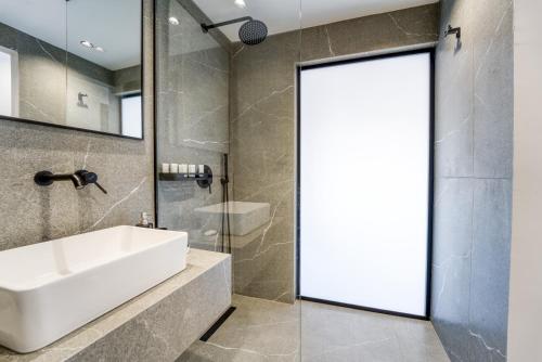 a bathroom with a white sink and a glass door at Island Sea Side Hotel - Adults Only in Rhodes Town
