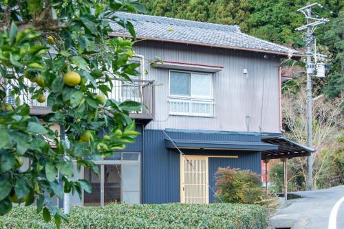 a blue and white house with a tree at Atelier&guesthouse ヌクリハウス in Ieyama