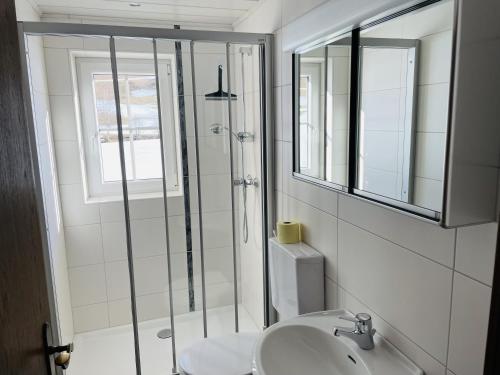 a white bathroom with a shower and a sink at Bergluft Appartement - Haus Lerchegger in Mössna