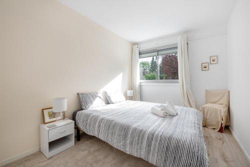 une chambre blanche avec un lit et une fenêtre dans l'établissement Le Corbusier - T3 atypique et spacieux, à Toulouse