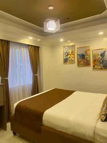 a bedroom with a bed and three paintings on the wall at MAKATI Isabela Luxury in Manila