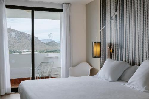 1 dormitorio con cama blanca y ventana grande en Bordoy Alcudia Bay - Adults Only, en Puerto de Alcudia