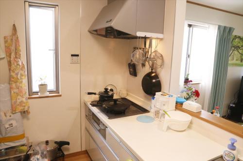 uma cozinha com um fogão, um lavatório e 2 janelas em 東京田園平安旅館 em Kawaguchi