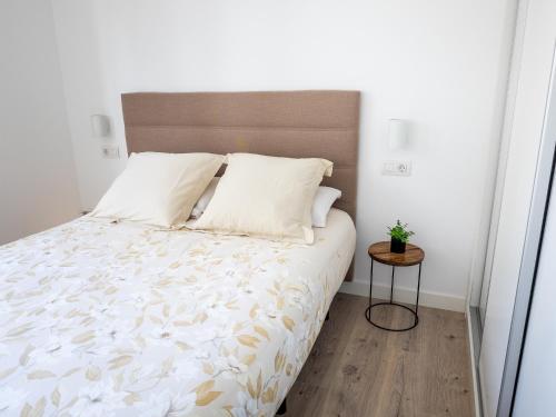 a bedroom with a bed with white sheets and a wooden floor at Apartment Abora with Pool, Gym and Free Parking in Las Palmas de Gran Canaria