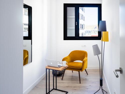a living room with a yellow chair and a table with a laptop at Apartment Abora with Pool, Gym and Free Parking in Las Palmas de Gran Canaria