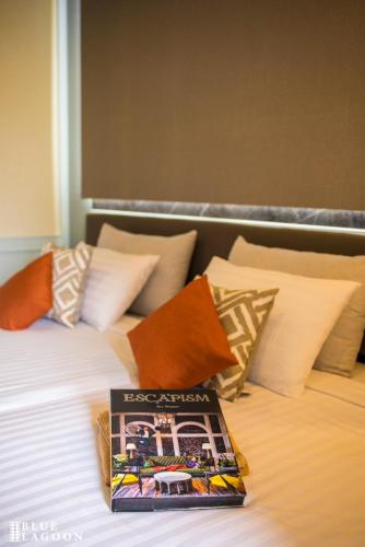 a book sitting on top of a bed with pillows at Blue Lagoon Hotel in Chiang Rai