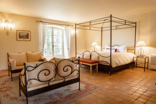 a bedroom with a four poster bed and a couch at Château les Crostes in Lorgues