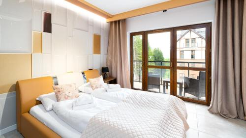 シュクラルスカ・ポレンバにあるGreen Park, Sun & Snowの白いベッドと大きな窓のある寝室