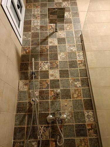 a shower in a bathroom with a tiled floor at WestLuxApartment in Al Karnak