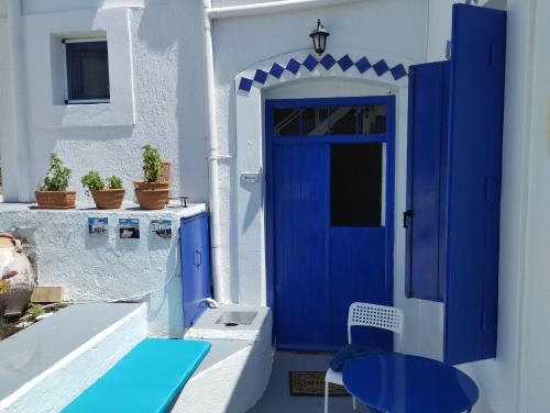 una puerta azul en un edificio blanco con una mesa y un Sidx Sidx de mesa azul en Mari...Milo, en Péran Triovasálos