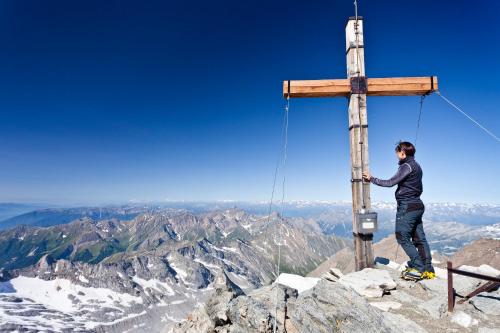 a man standing on top of a cross on a mountain at Hotel Brenner - Stop & Go in Vipiteno