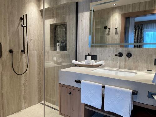 a bathroom with a shower and a sink and a mirror at Stock Resort in Finkenberg