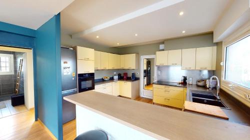 a kitchen with white cabinets and a blue wall at Cosy villa with pool near ocean in Labenne