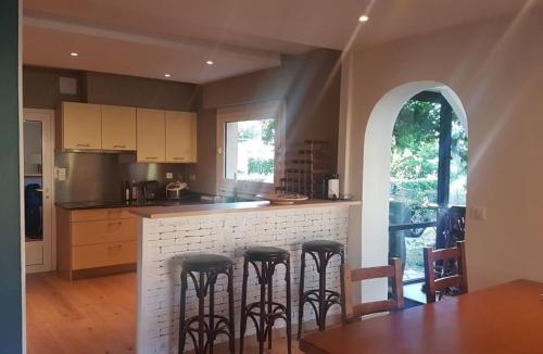 a kitchen with a bar with four stools at Cosy villa with pool near ocean in Labenne