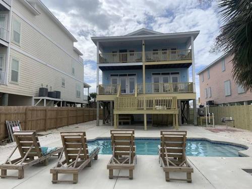 a house with two chairs and a swimming pool at Sandy Fox- Walk to Beach, Private pool, Sleeps 26 in Gulf Shores