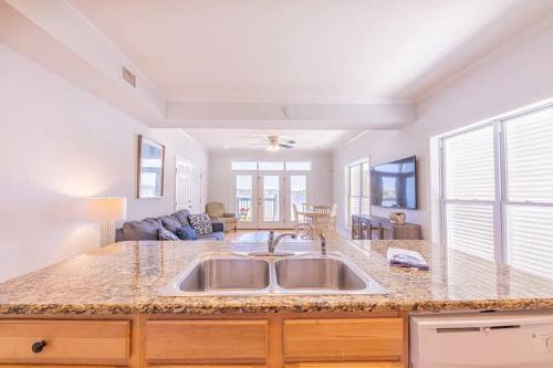 a kitchen with a sink and a living room at Sandy Fox- Walk to Beach, Private pool, Sleeps 26 in Gulf Shores