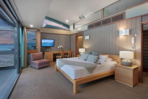 a bedroom with a bed and a desk and a tv at Yacht Club 33 Serenity House Ocean Views 2 Buggies in Hamilton Island