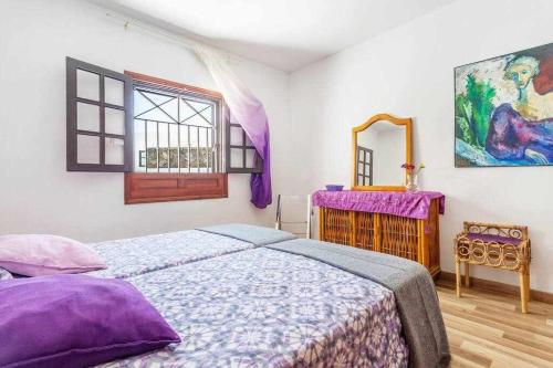 a bedroom with a bed with purple sheets and a mirror at Summer Dreams Beach House in Playa Honda