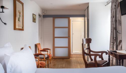 a bedroom with a bed and chairs and a window at Hôtel de la Plage in Plonévez-Porzay