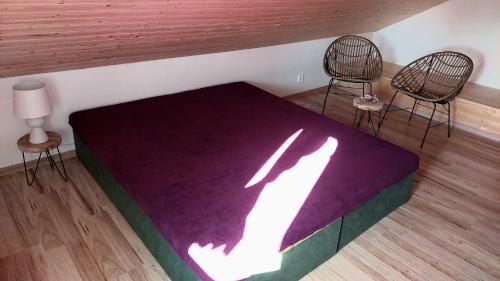 a bedroom with a purple bed and two chairs at Penzion Felden in Jablonné v Podještědí