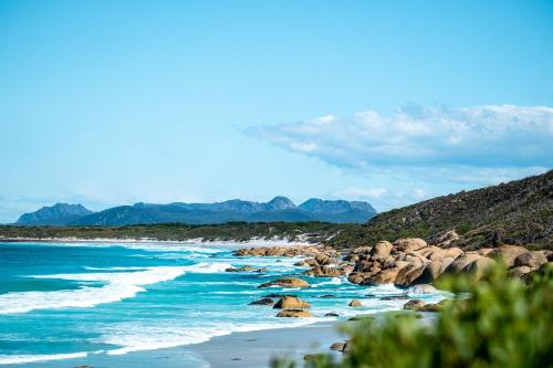 a beach with rocks and the ocean and mountains at Silver Moon at Half Moon in Bicheno